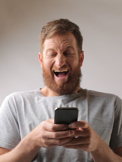 情绪一个留着胡子的男人为一条短信而兴奋的画像肖像欢呼商业