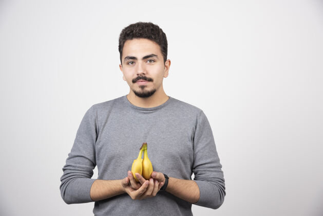 肖像一个年轻人拿着两个新鲜的香蕉脸手人
