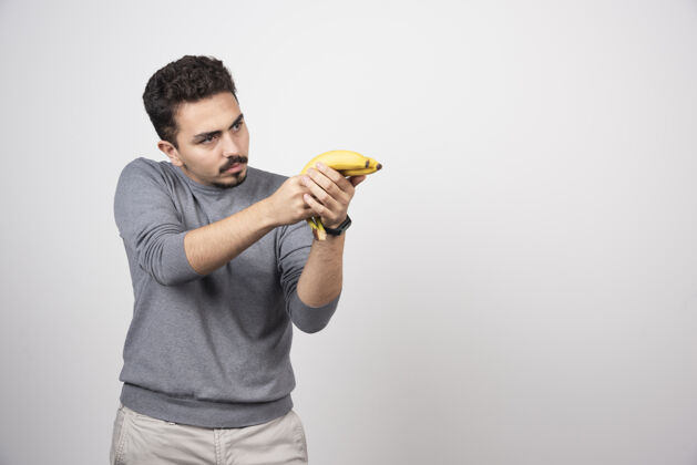 人一个年轻人拿着两个新鲜的香蕉人表情姿势