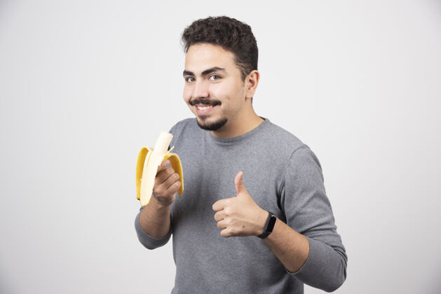 指向积极的年轻人拿着香蕉 竖起大拇指脸手臂人