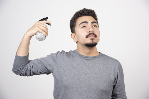 男人一个拿着塑料喷雾瓶的年轻人T恤瓶子胡子