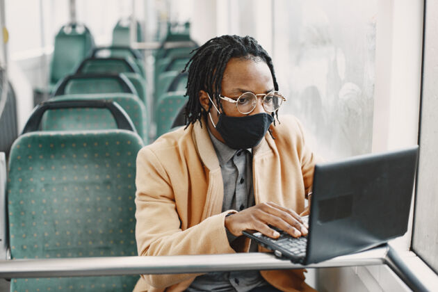 成人非裔美国人坐在城市巴士上穿棕色外套的家伙电晕病毒概念商人男子医疗