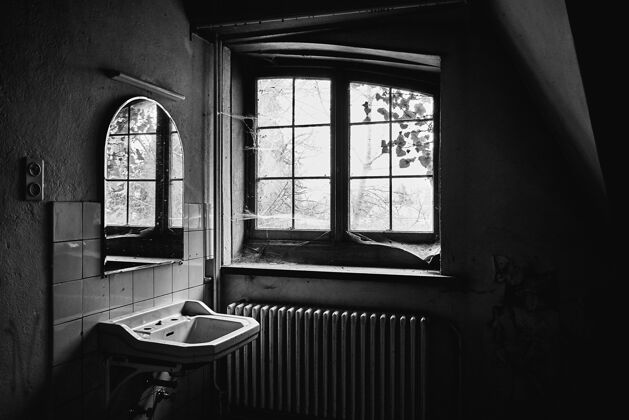 房间一个废弃房间的灰阶照片 里面有一个水槽 一面镜子 窗户上满是蜘蛛网光美丽空
