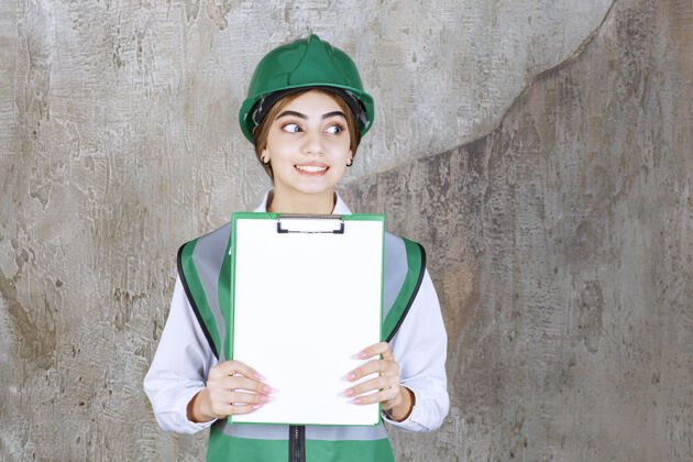 工程师身着绿色制服 头戴安全帽的女工程师展示项目清单建筑师雇员工人