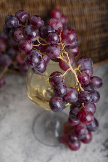 美食一杯白葡萄酒和新鲜的红葡萄放在石桌上杯红酒庄
