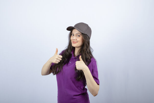 员工紫色制服的送货女孩站着竖起大拇指的肖像高质量的照片工作女帽子