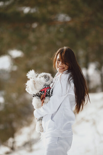 森林在冬季公园散步的可爱女孩穿着棕色夹克的女人牵着狗的女人休闲狗人
