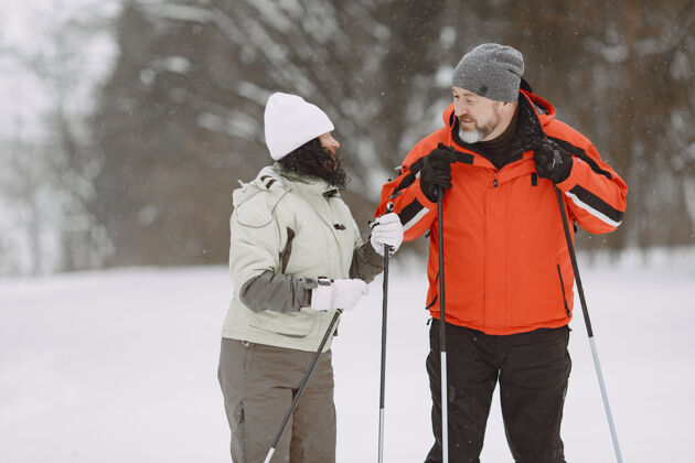 自然冬季公园里快乐的成年夫妇人们穿着运动服在森林里悠闲地跋涉成人公园成熟