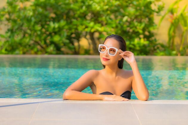 度假美丽的亚洲年轻女子在游泳池里放松的画像人热带海滩