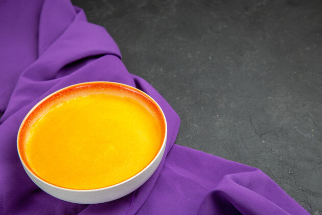 杯子前视图简单的南瓜汤在紫色的纸巾和深色的桌子上水果正面柑橘