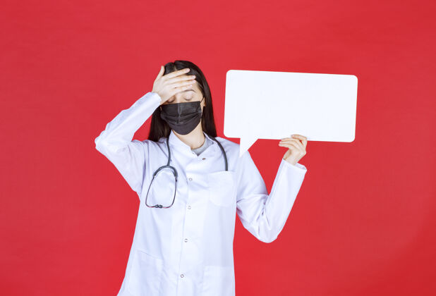 女人女医生带着听诊器 戴着黑色口罩 手里拿着一张长方形的问讯台 手里拿着头模特神经病毒