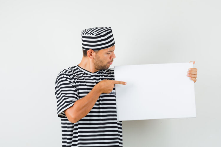 远景年轻男子指着一块空白的帆布 头戴条纹t恤帽 神情专注技术网站焦点条纹