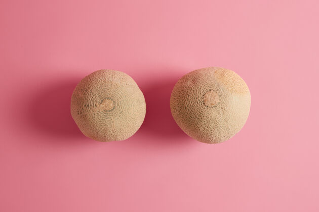 配料两个全熟美味的哈密瓜在玫瑰色的背景上拍摄夏季水果富含坚果 可以添加到你的饮食中 有高水分 帮助你保持水分甜点热带哈密瓜