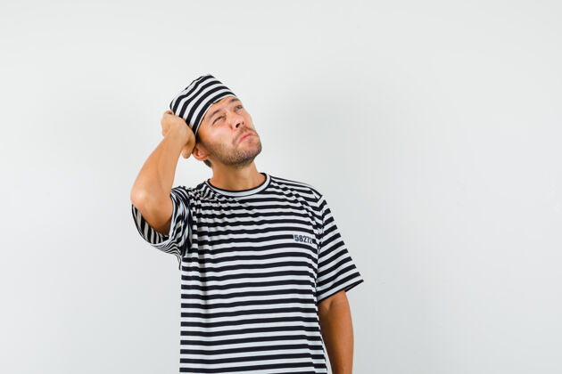 男一个戴着条纹t恤帽的年轻人抬起头来 神情沉思现代沉思帽子