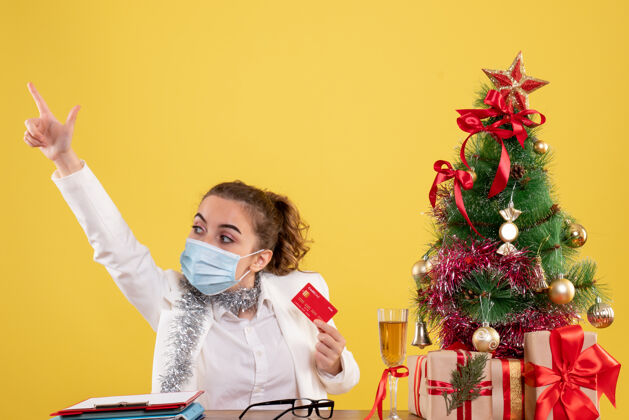圣诞节前视图戴面具的女医生拿着银行卡颜色银行病毒