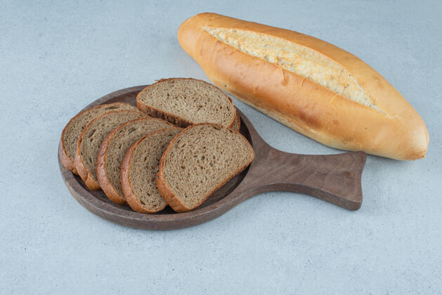 面包黑麦面包木板和面包卷放在石头表面健康黑麦切片