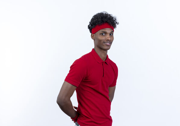 背部高兴的年轻黑人美国运动男子戴头带和腕带保持双手背后的白色背景隔离头带戴运动型