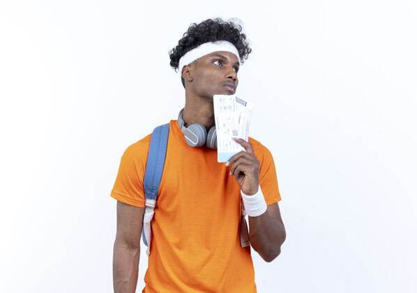 年轻看着一个戴着头带和腕带 拿着隔离在白色背景上的票 心不在焉的年轻的美国黑人运动型男人运动非裔美国人壁板