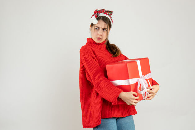 购物前视图激动的女孩与圣诞帽隐藏她的礼物帽子空间微笑