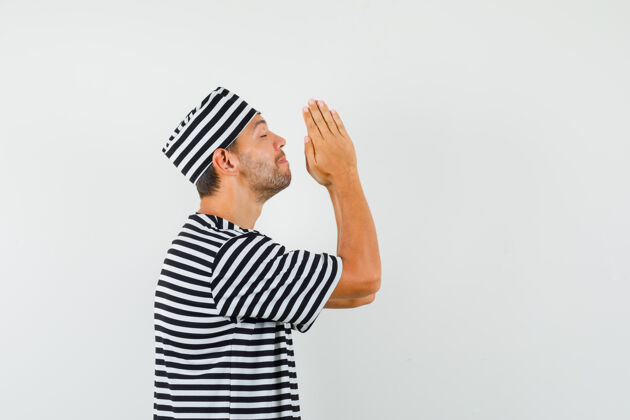 科技网年轻的男性手牵手祈祷的姿势在条纹t恤帽子和期待商务摄像头手势姿势