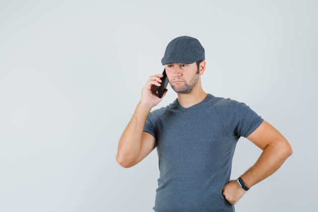 小一个戴着t恤帽的年轻男人在讲手机 看上去很悲伤手机接听电话远视