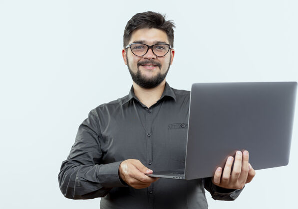 戴着高兴的年轻商人戴着眼镜拿着笔记本电脑隔离在白色背景上年轻人笔记本电脑商务人士