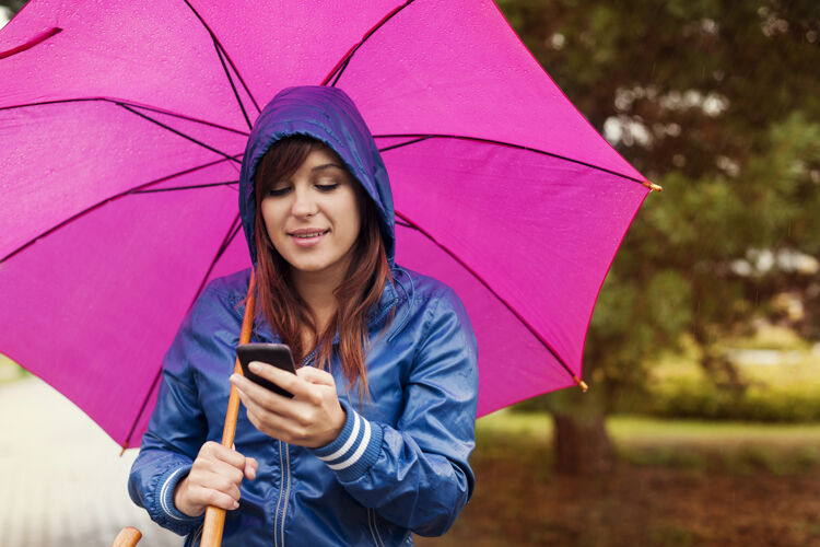 雨雨中用手机发短信的年轻女子成人笑女性