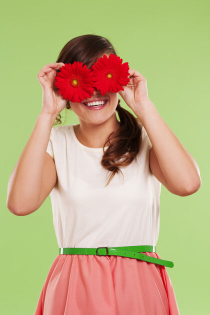 欢乐微笑的女人用两朵花遮住眼睛休闲活动垂直花