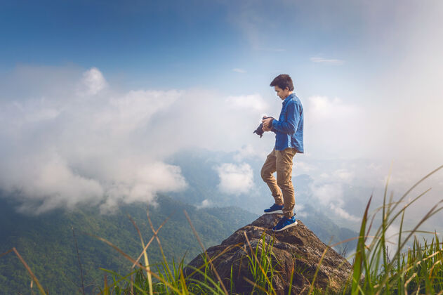 日出摄影师手拿相机 站在岩石上的自然旅游概念复古色调雾摄影师自然