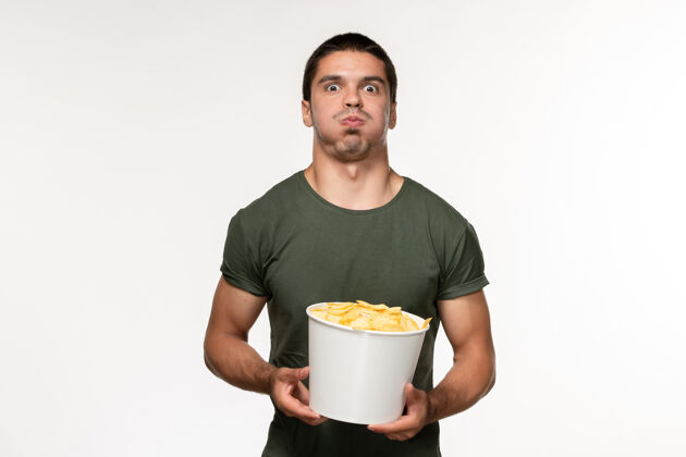 视图正面图身穿绿色t恤的年轻男性 白色书桌上有土豆cips电影人男性孤独电影电影院年轻男性桌子容器