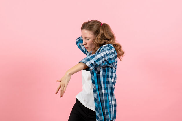 成人正面图穿着格子衬衫的年轻女性在粉色背景上跳舞年轻模特情感女童女青年格子人