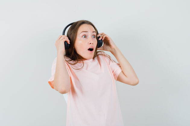 耳机穿着粉色t恤的年轻女孩摘下耳机 看上去很惊讶可爱搞笑头发