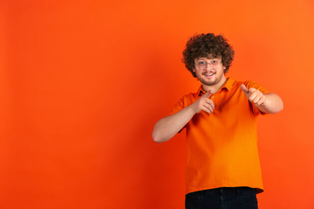 公司指着 选择你橙色工作室里白人年轻人的单色肖像事业财务年轻