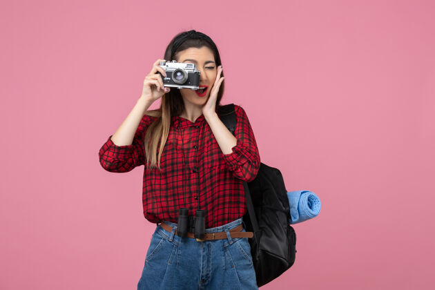 相机前视图年轻女性用相机在粉红色背景上拍照女性照片颜色年轻女性拍摄人