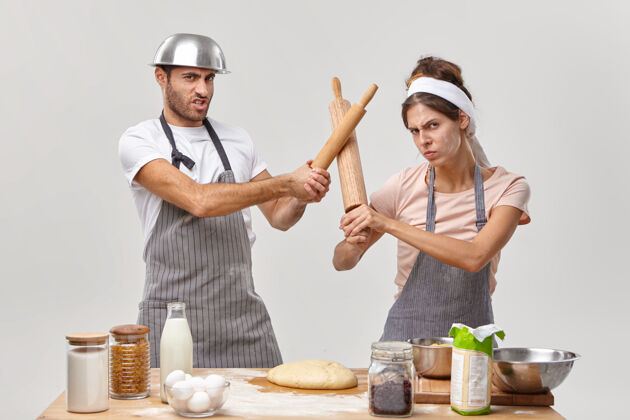 女专业厨师在厨房打仗 参加烹饪比赛 用擀面杖击剑 准备新鲜面团做烤派 做饼干甜点厨师比赛谁是最好的制服站立面粉