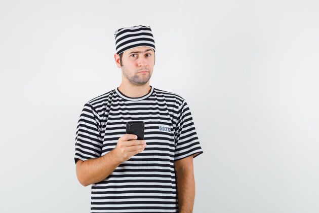 男人年轻男子拿着手机穿着t恤 戴着帽子 神情犹豫不决脸人手机