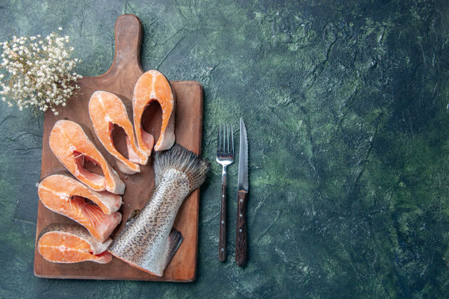 壁板上图：新鲜生鱼放在木质砧板上 刀子放在深色混色桌的右侧 空间宽敞刀片工具木头