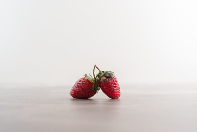 两个两个新鲜草莓放在大理石桌上有机新鲜草莓