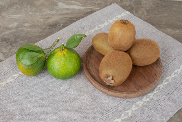 桌布在灰色桌布上放上奇异果和新鲜橘子天然水果叶子