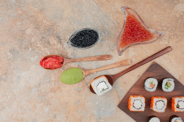 酱油美味的寿司 鱼子酱 姜和瓦萨比放在木盘上汤匙米饭鱼子酱