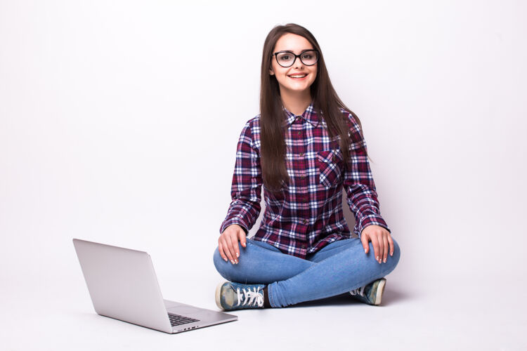 女性在白色背景的地板上操作笔记本电脑的年轻女子女士深色头发成年人