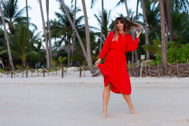 优雅日落时分 在热带白色沙滩上 身着红色夏装的白种人女人洋溢着浪漫快乐的心情海岸海岸时尚