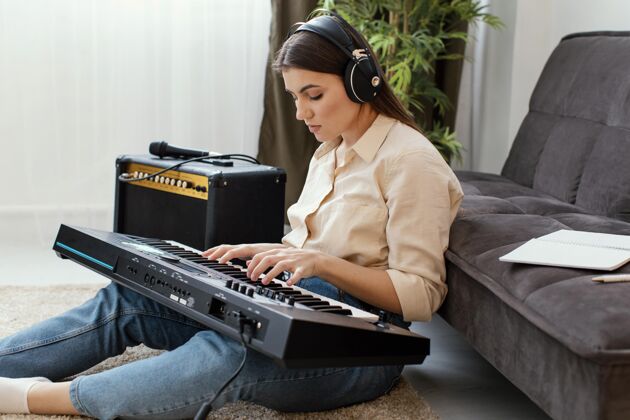音乐家戴着耳机弹奏钢琴键盘的女音乐家侧视图家用耳机房子