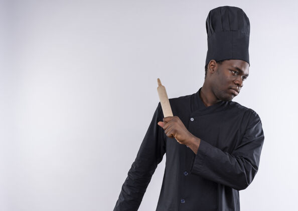 空间年轻自信的非洲裔美国厨师身着厨师制服 手持擀面杖 看着白色的一面 留有复印空间复制制服烹饪