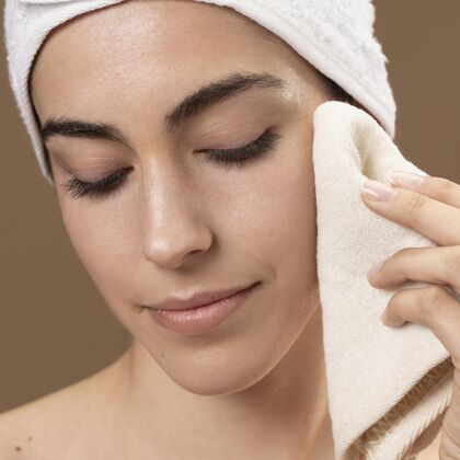 女人年轻女人用毛巾摸她的脸美容护理眉毛治疗