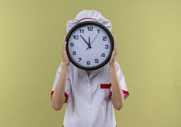 时钟身着厨师制服的年轻白种人厨师女孩用绿色的时钟和复制空间合上脸烹饪制服空间