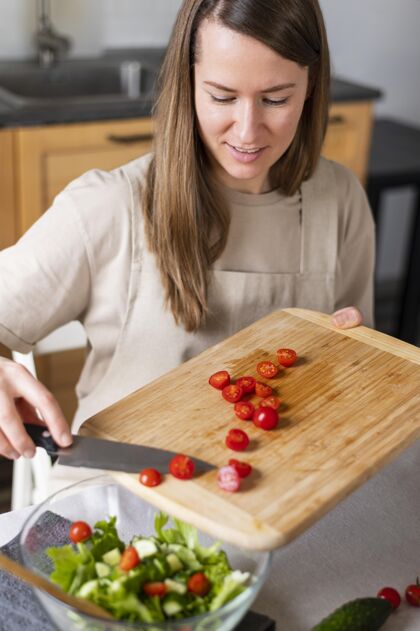 美味特写镜头 一个在沙拉里放西红柿的女人室内烹饪房子