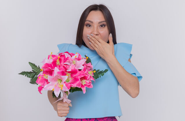 国际身着蓝色连衣裙的亚洲女人捧着一束鲜花 开心又惊喜地捂着嘴花惊喜花束