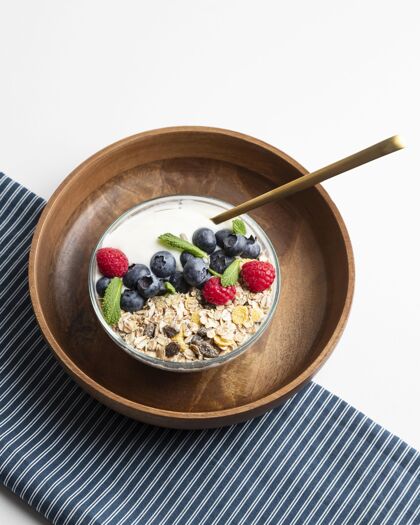 饭高角度的燕麦片碗与覆盆子和蓝莓勺子早餐垂直
