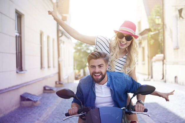 继续一对夫妇开着摩托车穿过城市城市街道骑阳光